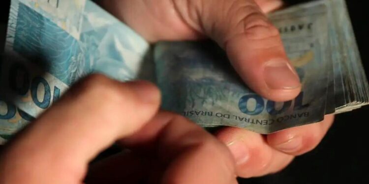 Um estudante contando o dinheiro que ganhou no Caixa Tem