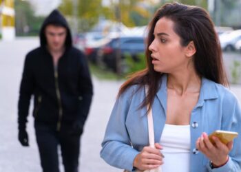 Uma mulher desesperada com alguém atrás dela, pensa em fazer um Boletim de Ocorrência