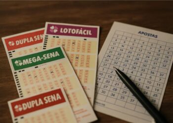 Imagem de bilhetes das Loterias Caixa em cima da mesa, incluindo a Mega-Sena