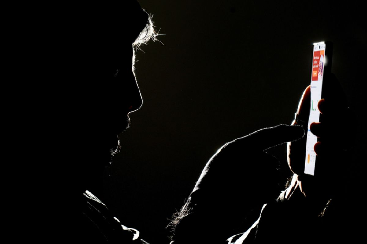 Uma pessoa com o celular na mão, pensando se está caindo no golpe da falsa venda