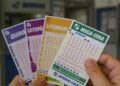 Uma pessoa com bilhetes das loterias Caixa após apostar pela Surpresinha