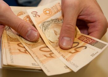 Uma pessoa com notas de R$ 50,00, do 13º salário