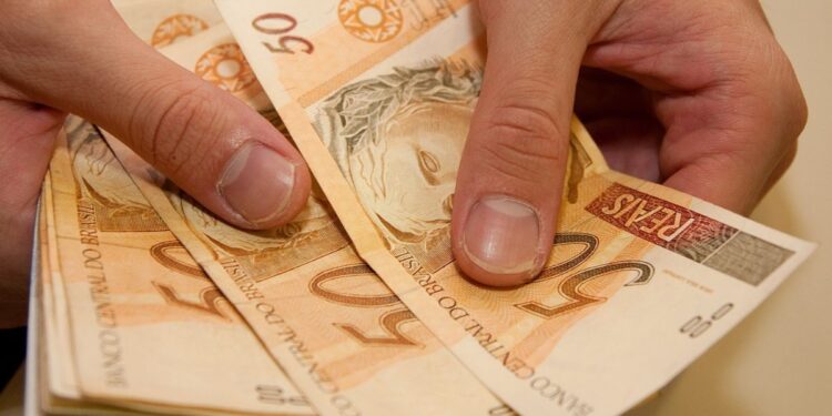 Uma pessoa com notas de R$ 50,00, do 13º salário