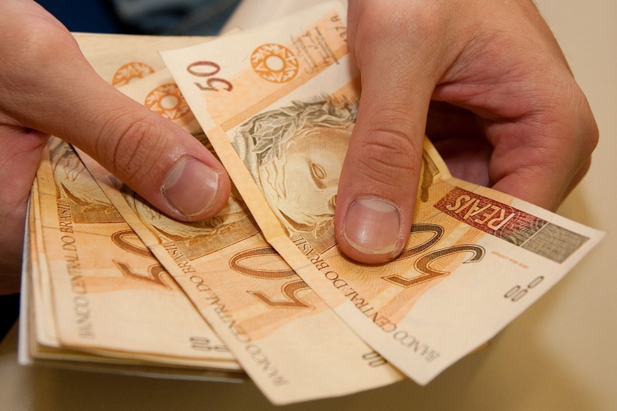 Uma pessoa com notas de R$ 50,00, do 13º salário