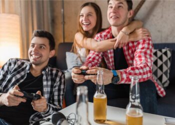 Dois amigos jogando (um está ao lado de sua namorada que o abraça), e com sorte no amor