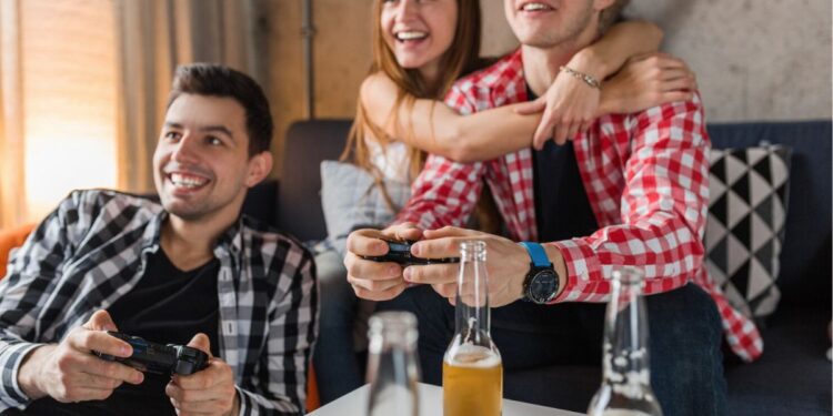 Dois amigos jogando (um está ao lado de sua namorada que o abraça), e com sorte no amor