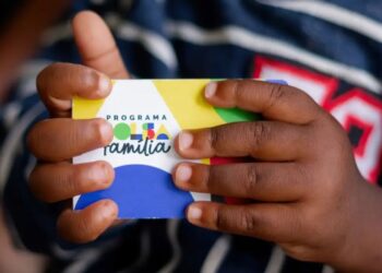 Um cartão na mão de uma criança que recebe o Bolsa Família