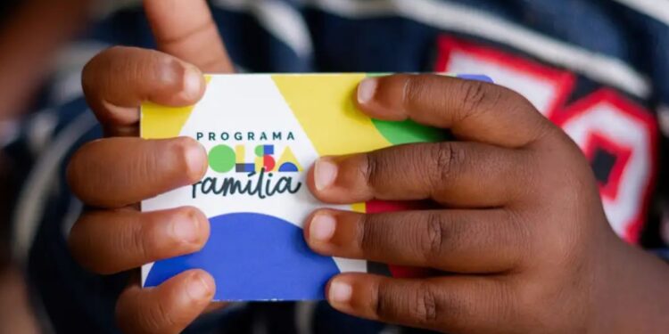 Um cartão na mão de uma criança que recebe o Bolsa Família