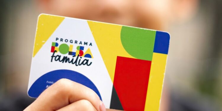 Uma criança segura o cartão do Bolsa Família antes de ser bloqueado