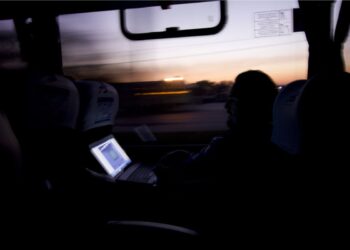 Um dos brasileiros dentro de um ônibus na Finlândia com um notebook aberto