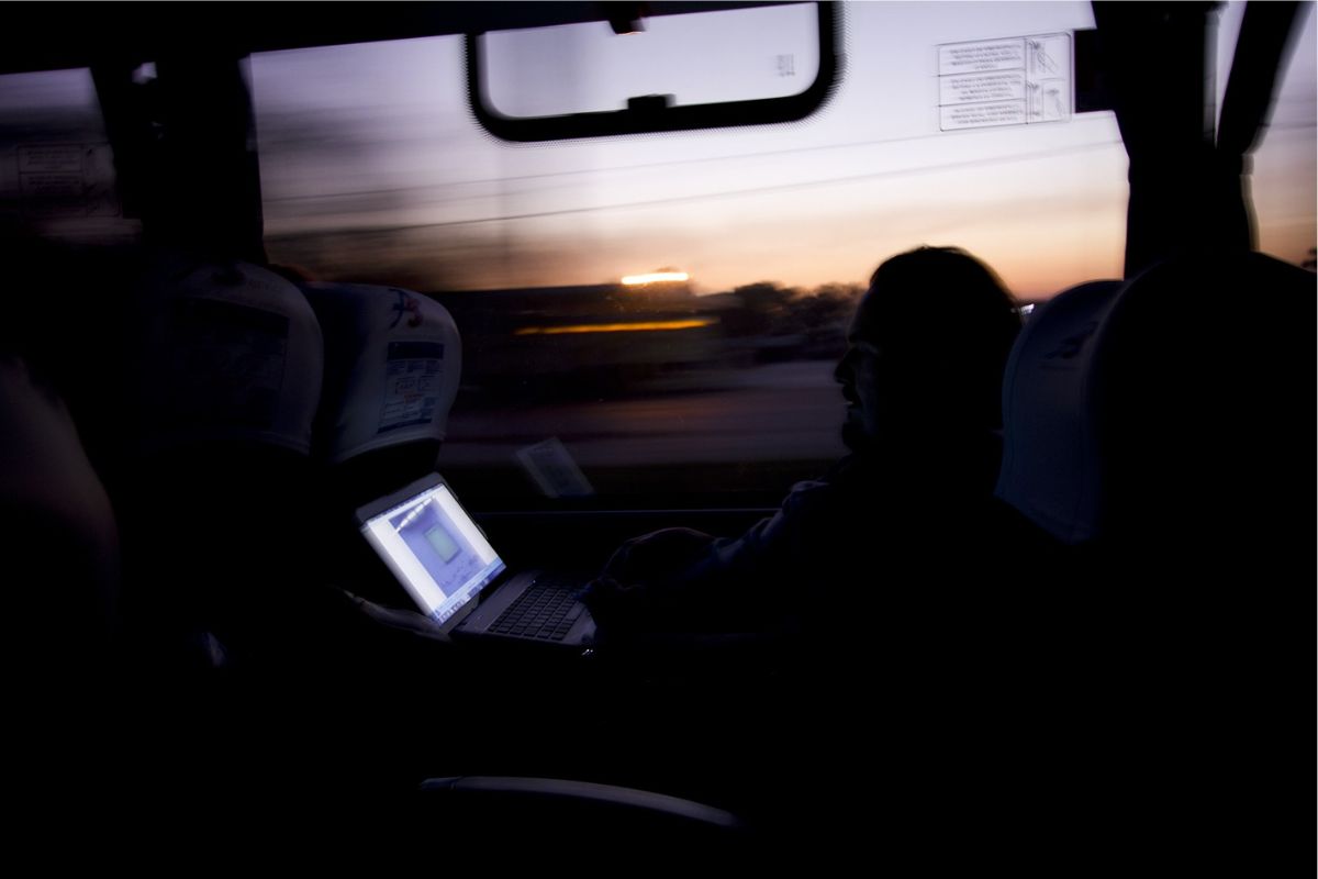 Brasileiro dentro de um ônibus na Finlândia com um notebook aberto