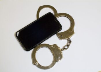 Olhar o celular do parceiro sem permissão pode dar cadeia? Um celular ao lado de uma algema