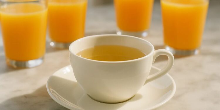 Uma xícara de chá branco, ao fundo 4 copos de suco de laranja