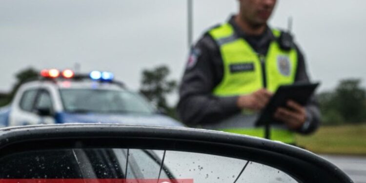 Um guarda vindo em direção ao carro para aplicar a multa da Lei do retrovisor