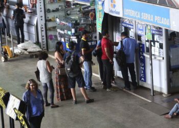 Pessoas em frente a uma agência da Caixa Econômica para apostar na Mega da Virada