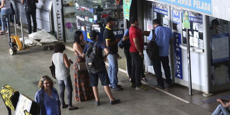 Pessoas em frente a uma agência da Caixa Econômica para apostar na Mega da Virada