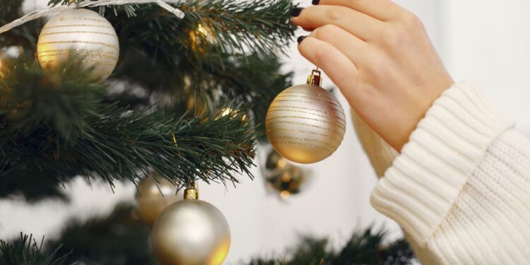 Uma pessoa enfeitando a árvore de natal
