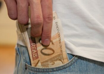 Uma pessoa coloca notas de 50 reais do PIS e PASEP