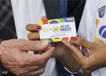 Uma jovem segura o cartão do Programa Pé-de-meia