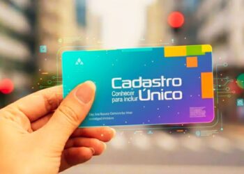 Uma mão segura o cartão do Cadastro Único azul