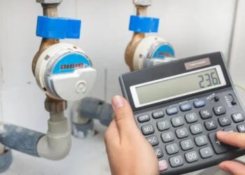 Imagem de uma calculadora em frente ao hidrômetro para calcular a conta de água