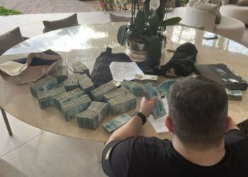 Um agente da polícia federal contando notas de R$ 100,00