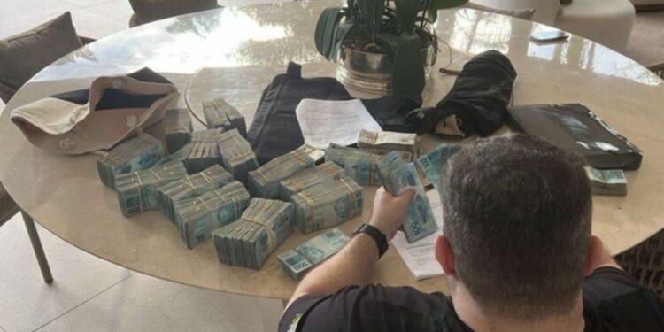 Um agente da polícia federal contando notas de R$ 100,00