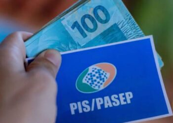 Cartão do Pis/Pasep e R$ 100,00 na mão de uma pessoa