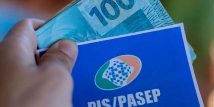 Cartão do Pis/Pasep e R$ 100,00 na mão de uma pessoa