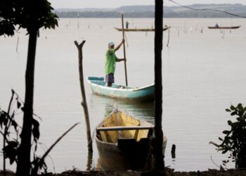 Pescador em um barco no Rio onde vai pescar peixes