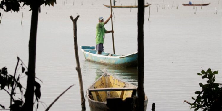 Pescador em um barco no Rio onde vai pescar peixes