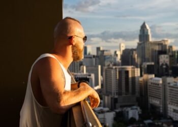 Um idoso com isenção de IPTU olhando para a cidade da sacada do seu prédio