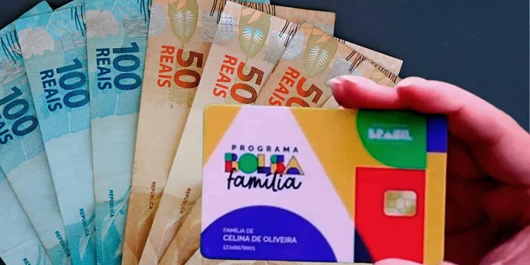 Uma pessoa segura o dinheiro e o cartão do Bolsa Família