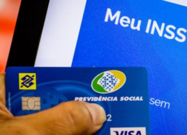 Uma pessoa segura seu cartão, ao fundo está o aplicativo MEU INSS