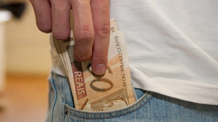 Uma pessoa colocando dinheiro no bolso após pedir um empréstimo rápido para emergências em 2026