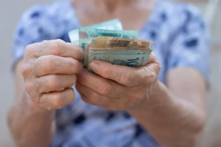 Uma mulher segurando dinheiro, comemorando à menor taxa de desemprego dos últimos anos