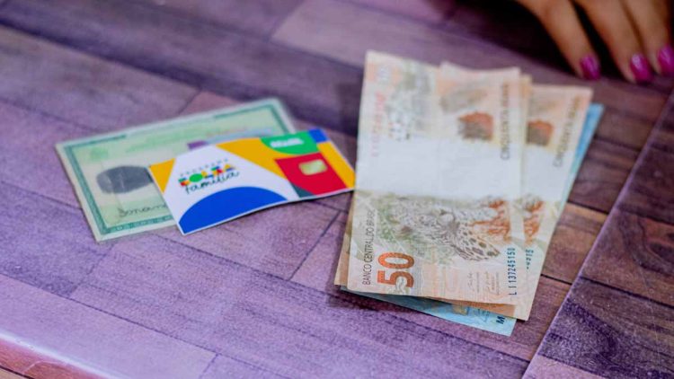 Dinheiro do 13º do Bolsa Família ai lado de um RG e o cartão do benefício