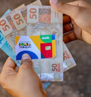 Na mão de uma pessoa estão três notas de R$ 50,00 e uma de R$ 100,00, além do cartão do benefício depois que o Governo Lula confirma importante ajuste no Bolsa Família de 623 cidades