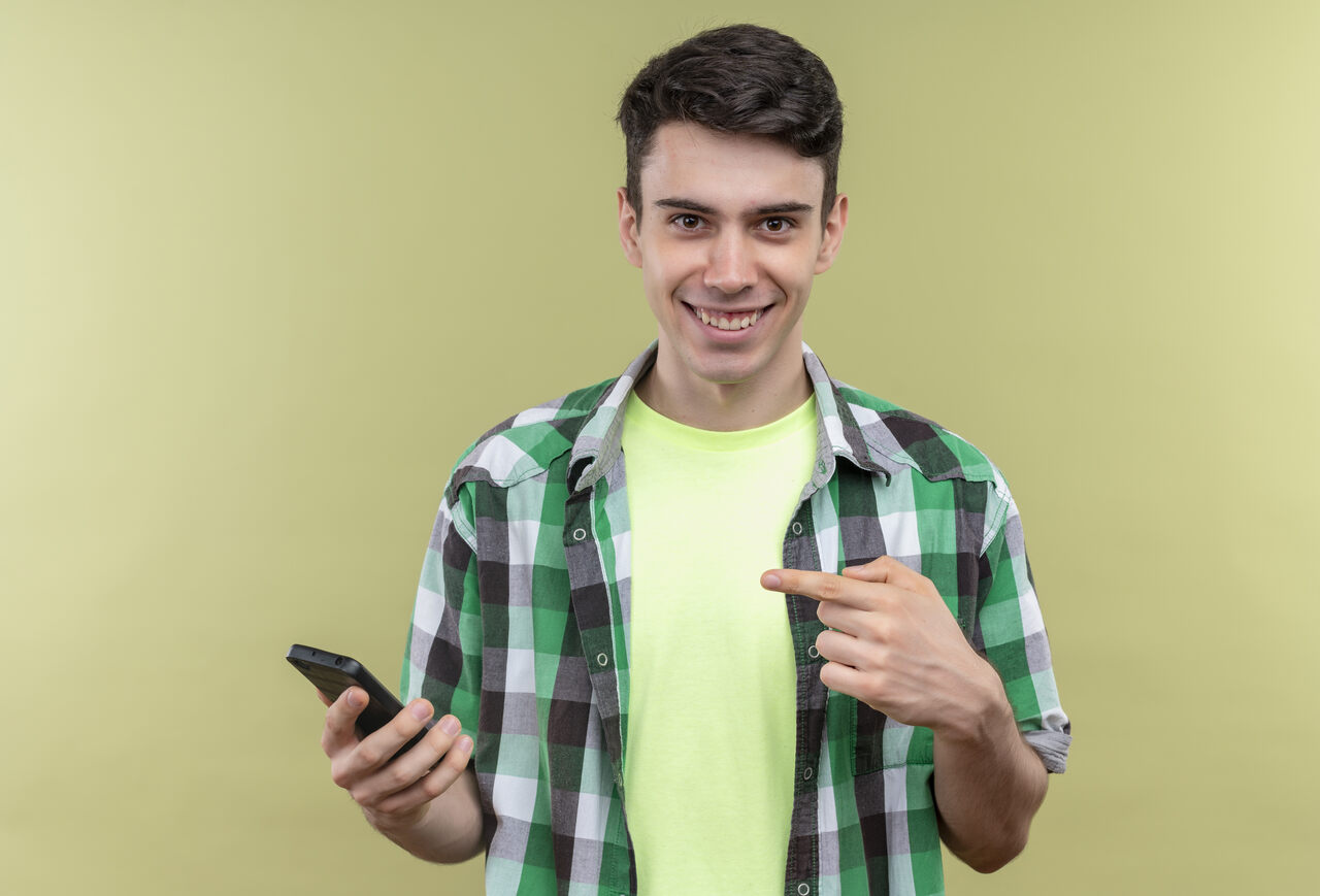 Jovem animado aponta para celular em sua mão