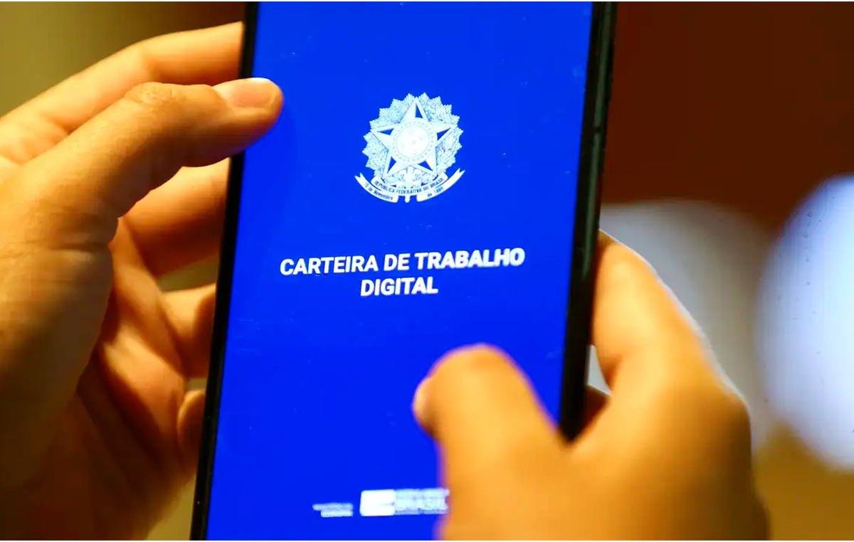 Close na mão de uma pessoa acessando a carteira de trabalho no celular