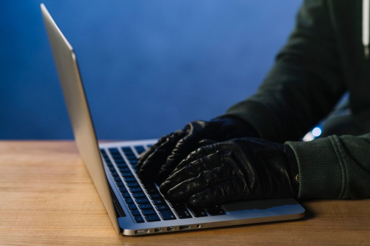 Um hacker tecla usando luva de couros, reforçando que o Banco Central NÃO envia links