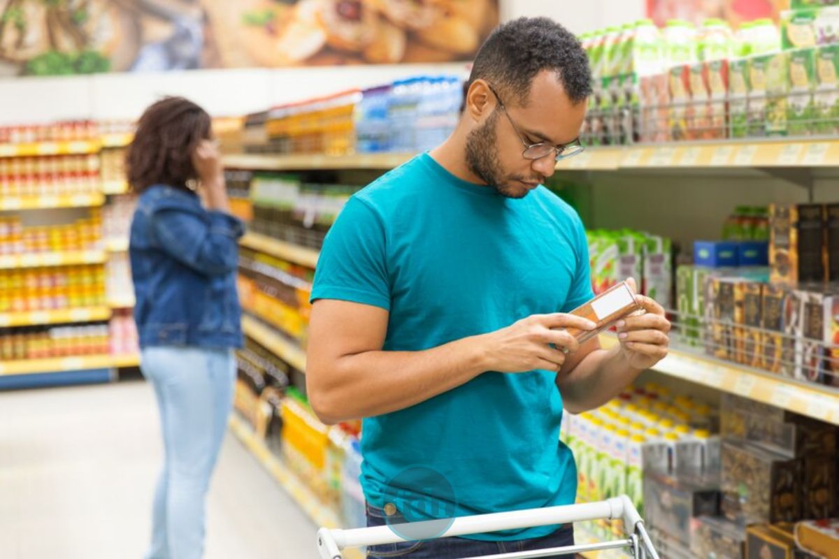 Um homem olha o rótulo do produto em sua mão após ver que a Cesta básica ideal custa R$ 432 