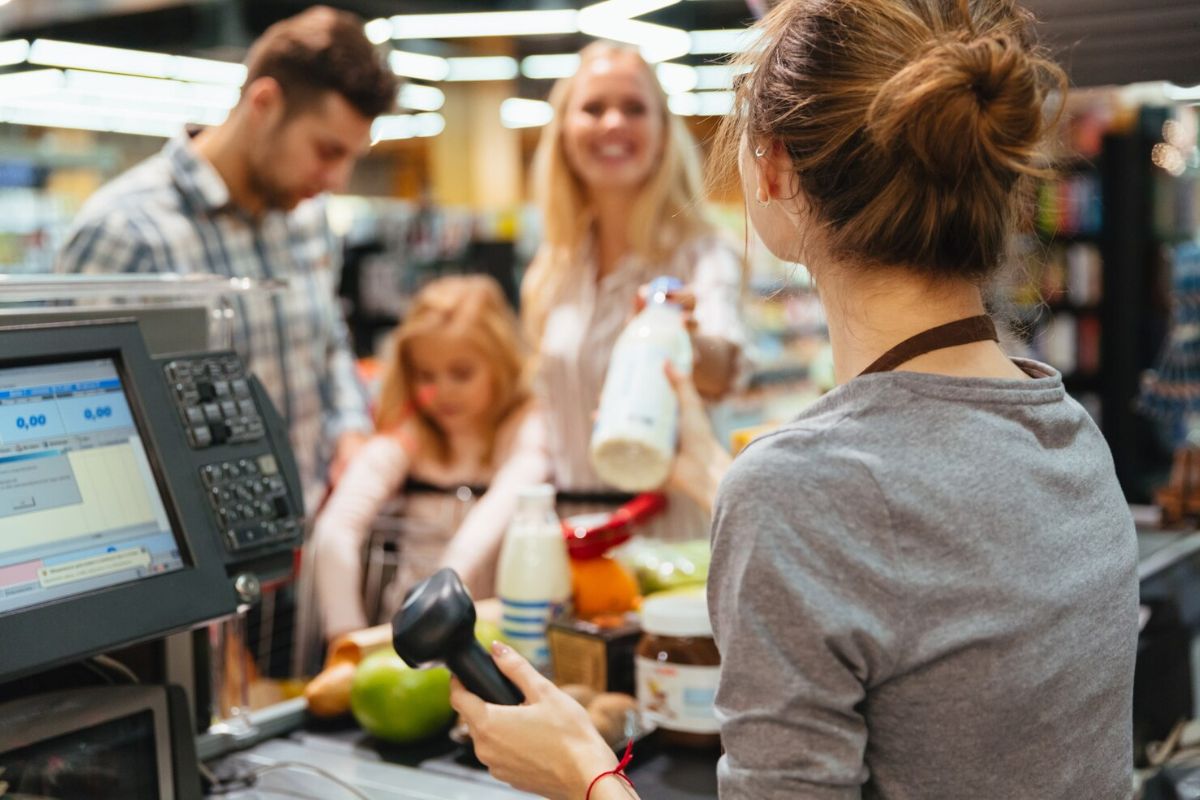 Uma família passando pelo caixa depois de aprender Como fazer compras inteligentes no supermercado