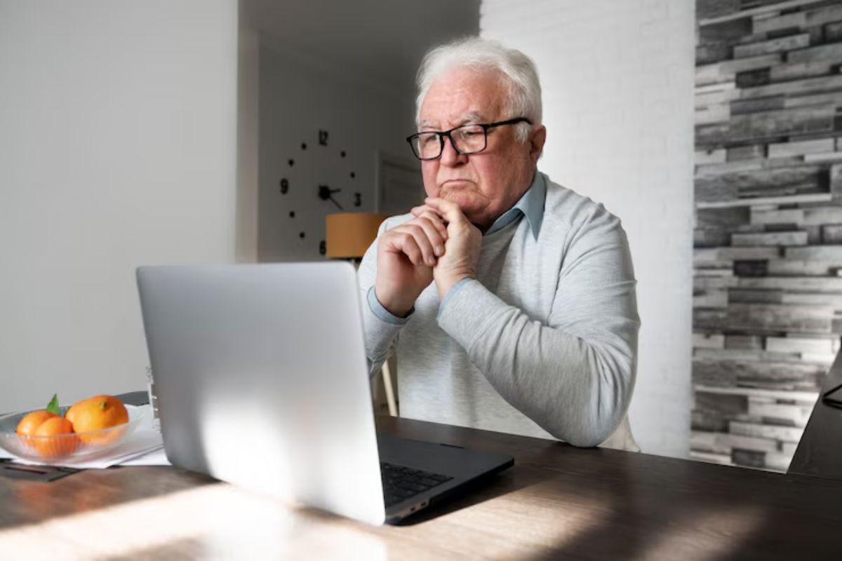 Um senhor com notebook vê como pedir a aposentadoria sendo MEI