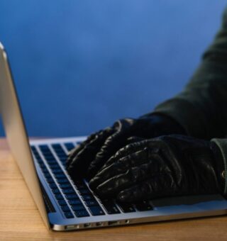 Um hacker tecla usando luva de couros, reforçando que o Banco Central NÃO envia links