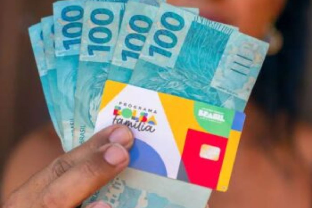 Uma moça com o dinheiro de benefício depois de ver que o Bolsa Família continuará