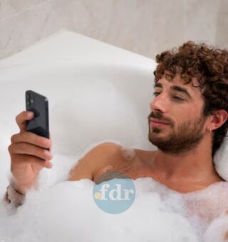 Um rapaz fazendo este hábito no banho: mexer no celular