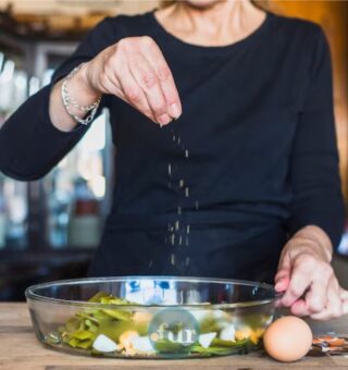 Uma mulher tempera a comida que tem o mineral essencial