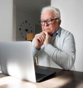 Um senhor com notebook vê como pedir a aposentadoria sendo MEI