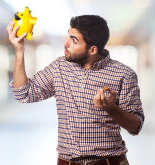 Um homem segura um cofrinho, ele está feliz após realizar o saque-aniversário do FGTS